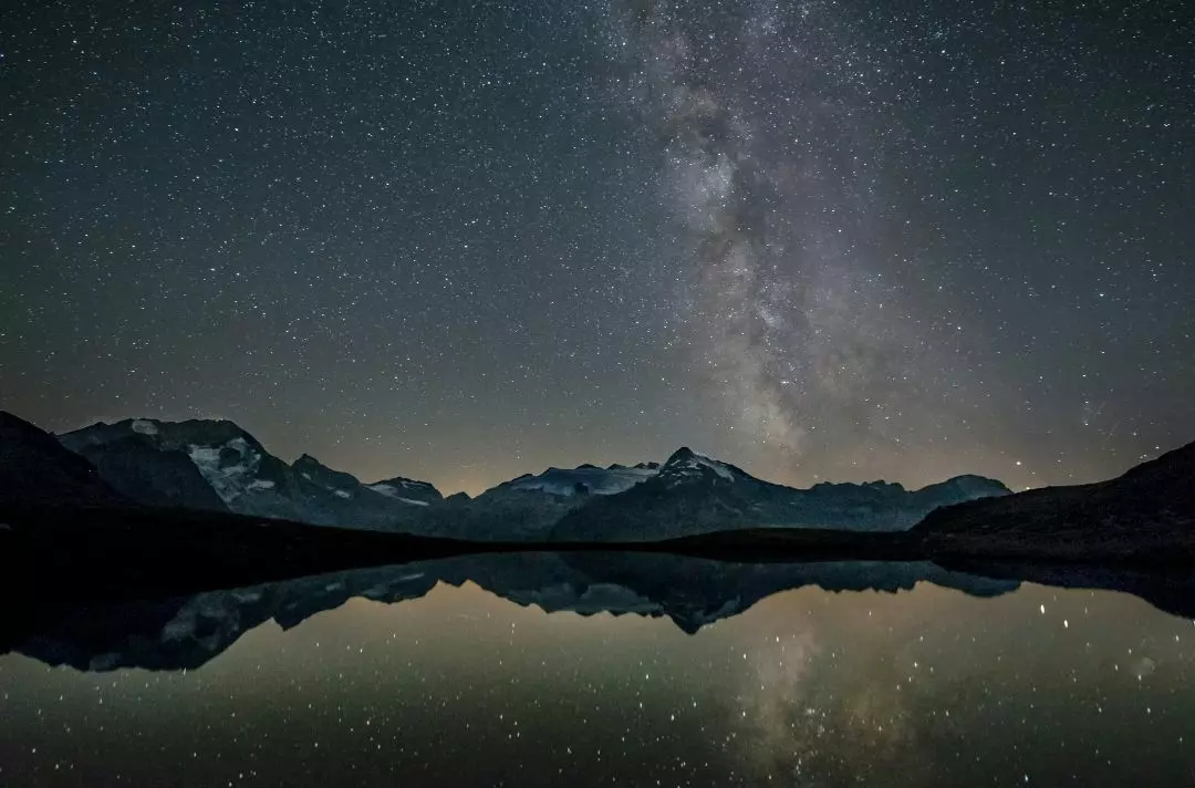 An icy mountain range and lake lit up by starlight.