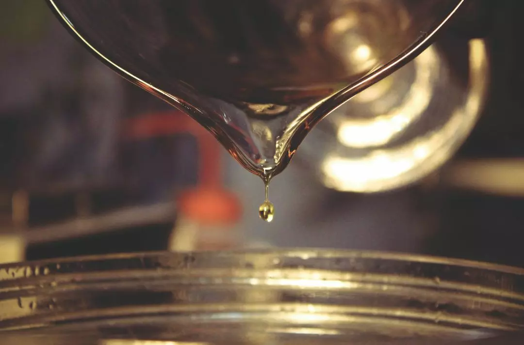 A glass jar of perfume being poured.