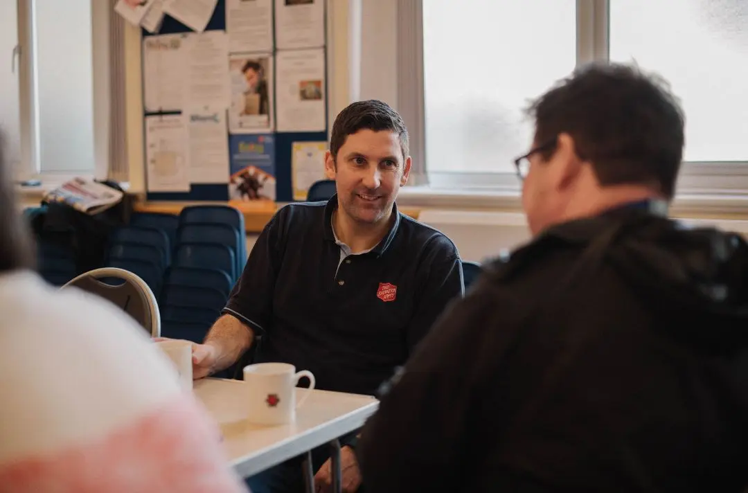 A Salvation Army officer having a coffee and a chat with a man 