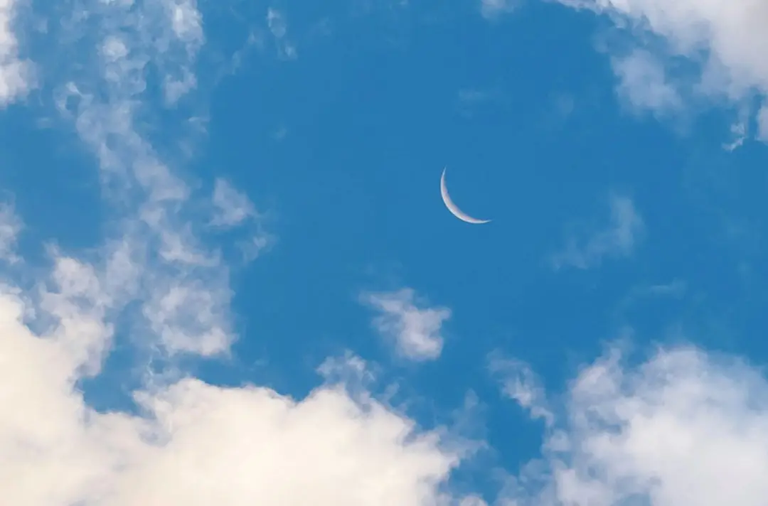 A photo of the sky with a crescent moon and clouds