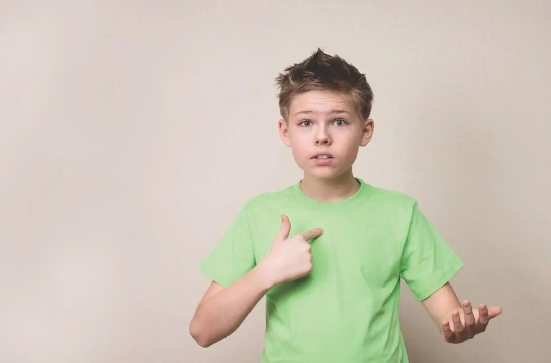 A boy points to himself as if to imply he is being accused of something