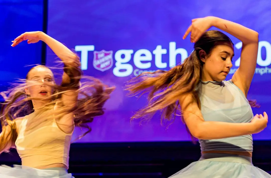 A photo of two young women dancing on stage at a Salvation Army event
