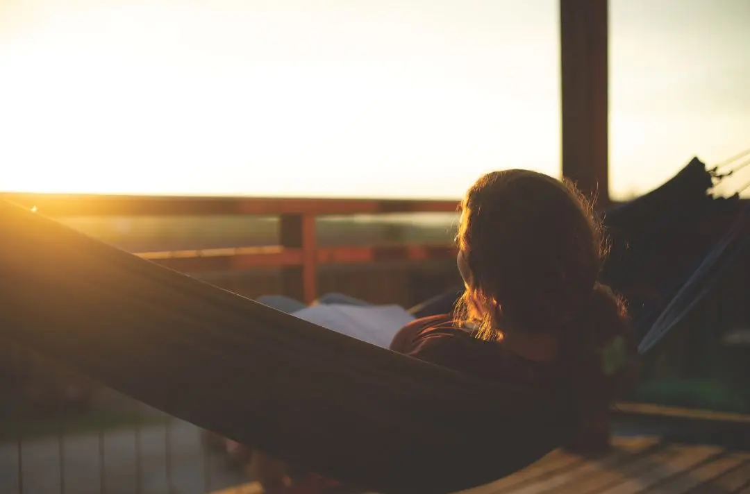 A woman looks out upon a sunset.