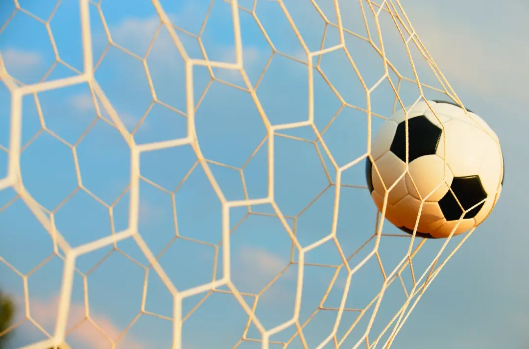 A photo shows a football hitting the back of a net.