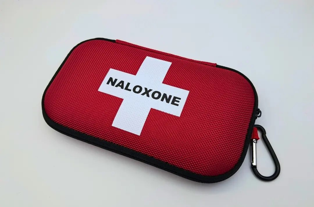 A photo shows a red kit with the text "naloxone" emblazoned across the front.