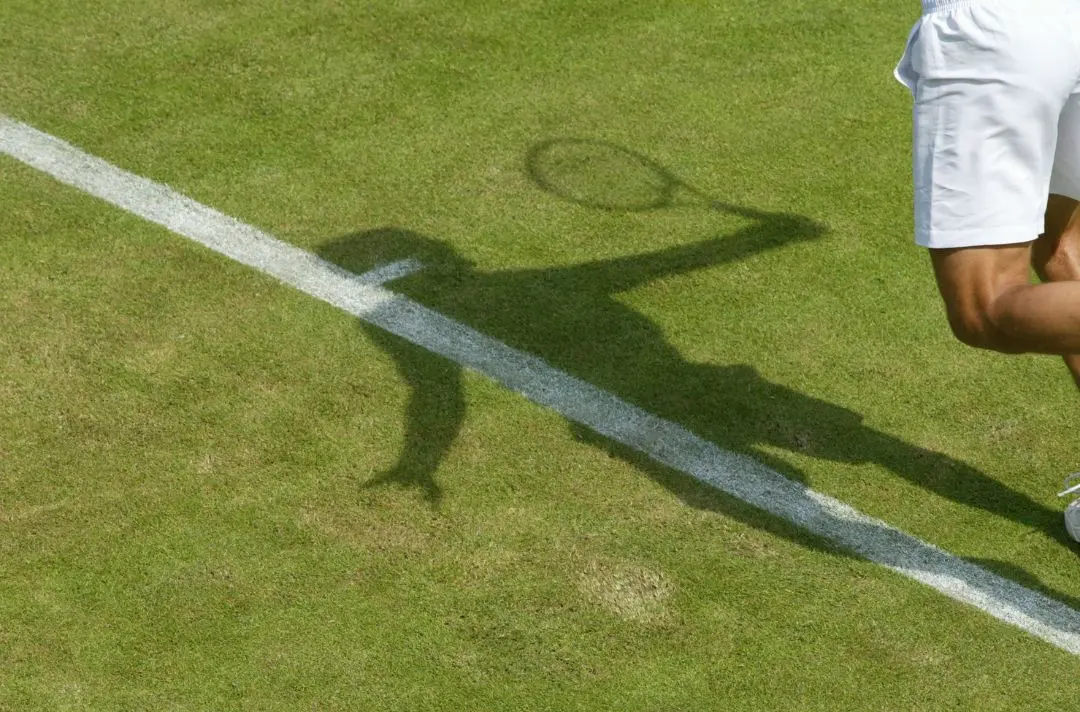 Shadow of a tennis player on the grass