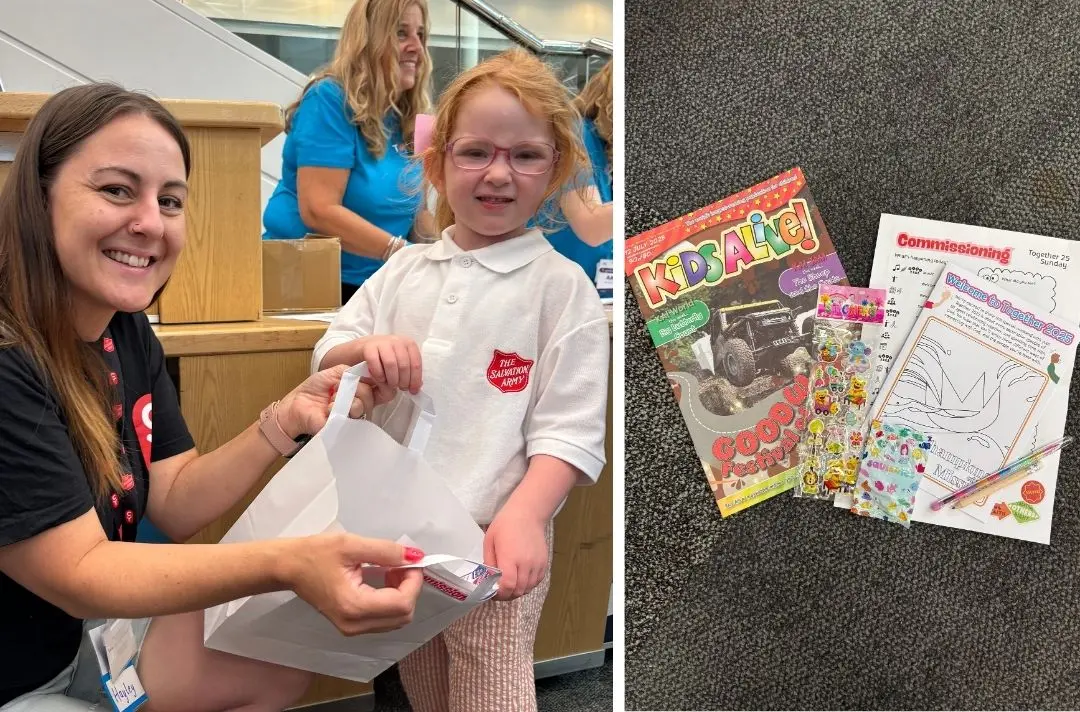 A photo of a children's worker handing an activity bag to a child wearing a red shield polo shirt