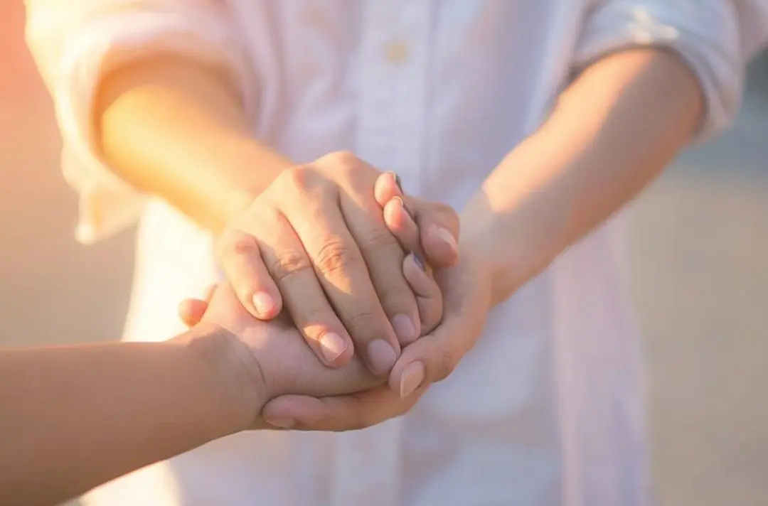 Two people holding each others' hands.
