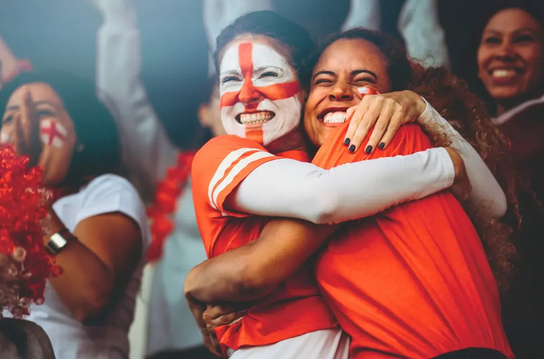 A photo shows two people in face paint hugging and celebrating.