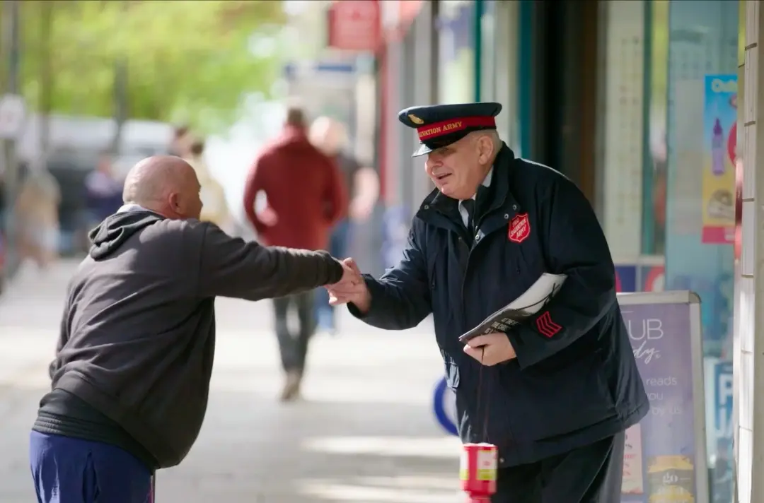 A photo shows someone in Salvation Army uniform greeting a passer-by.