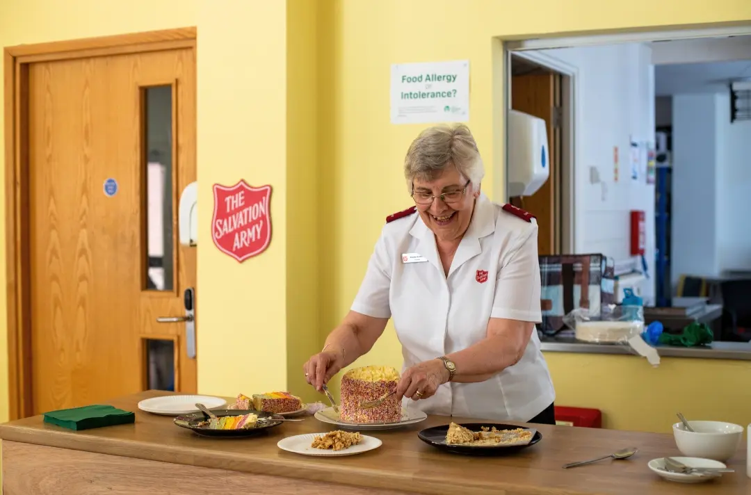 A photo shows someone in Salvation Army uniform serving cake.