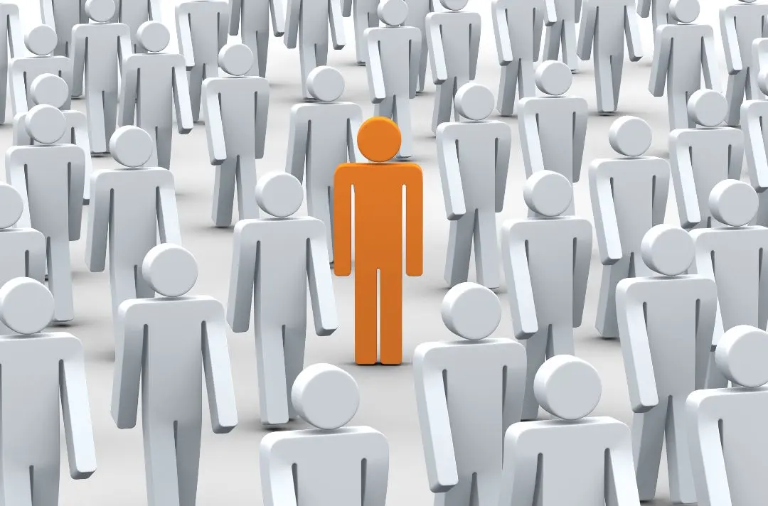 Orange stick man standing among lots of grey stick men