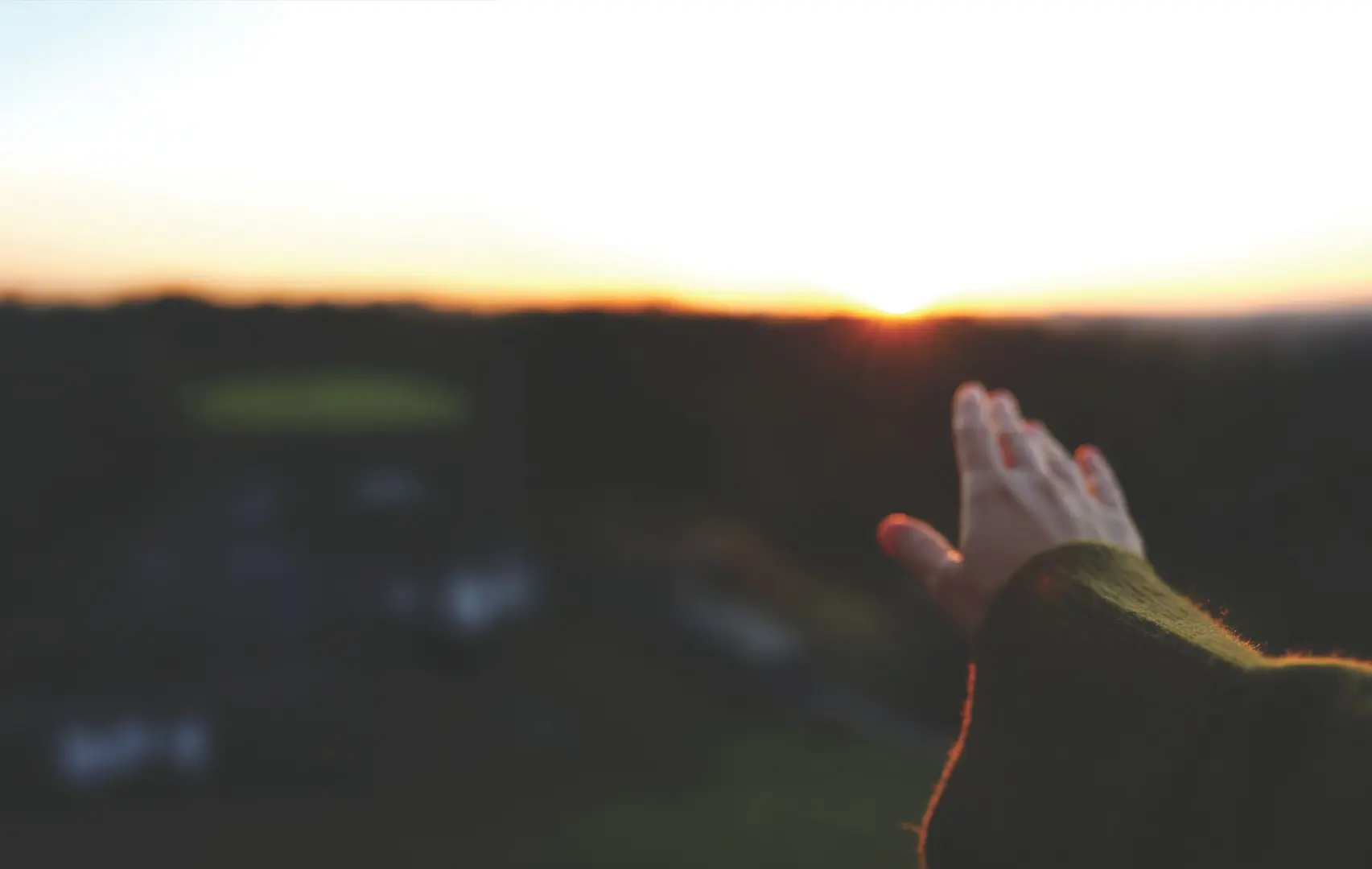A hand held out to a sunset.