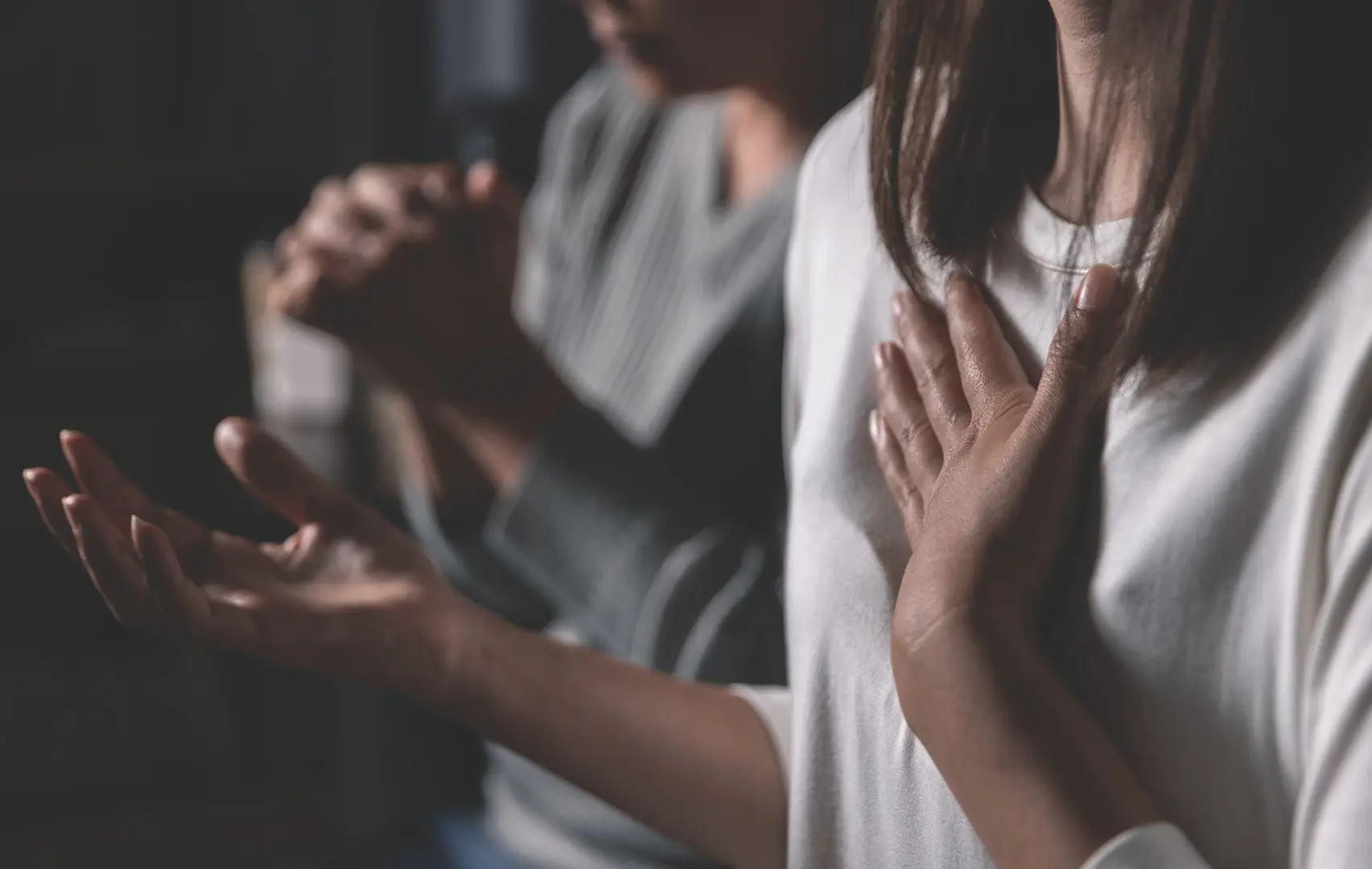 Two women praying with hands clasped.