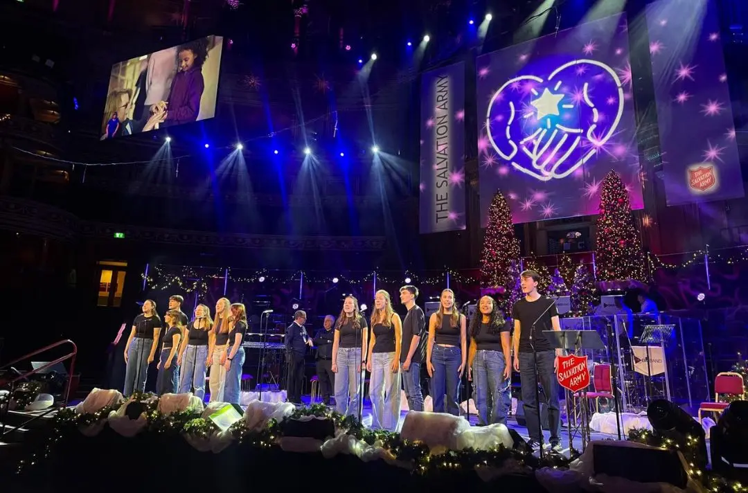 People on stage singing in front of microphones rehearsing at The Royal Albert Hall