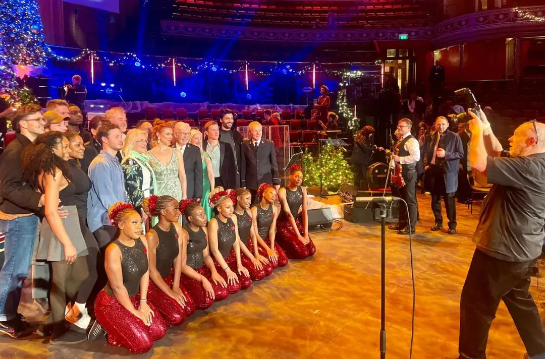 A group shot of performers being photographed on stage at the Royal Albert Hall after the performance
