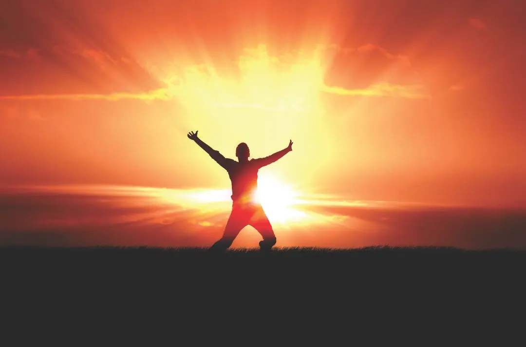 A man celebrates in the glory of the sun.