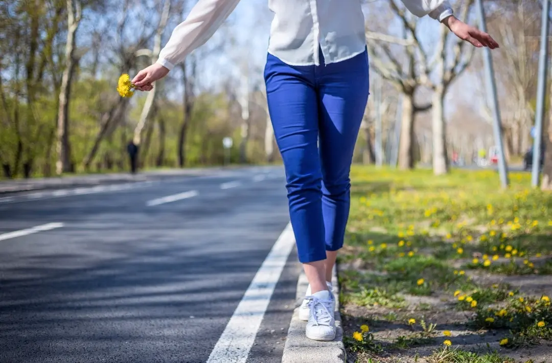 A photo shows someone keeping their balance while walking along a roadside kerb.