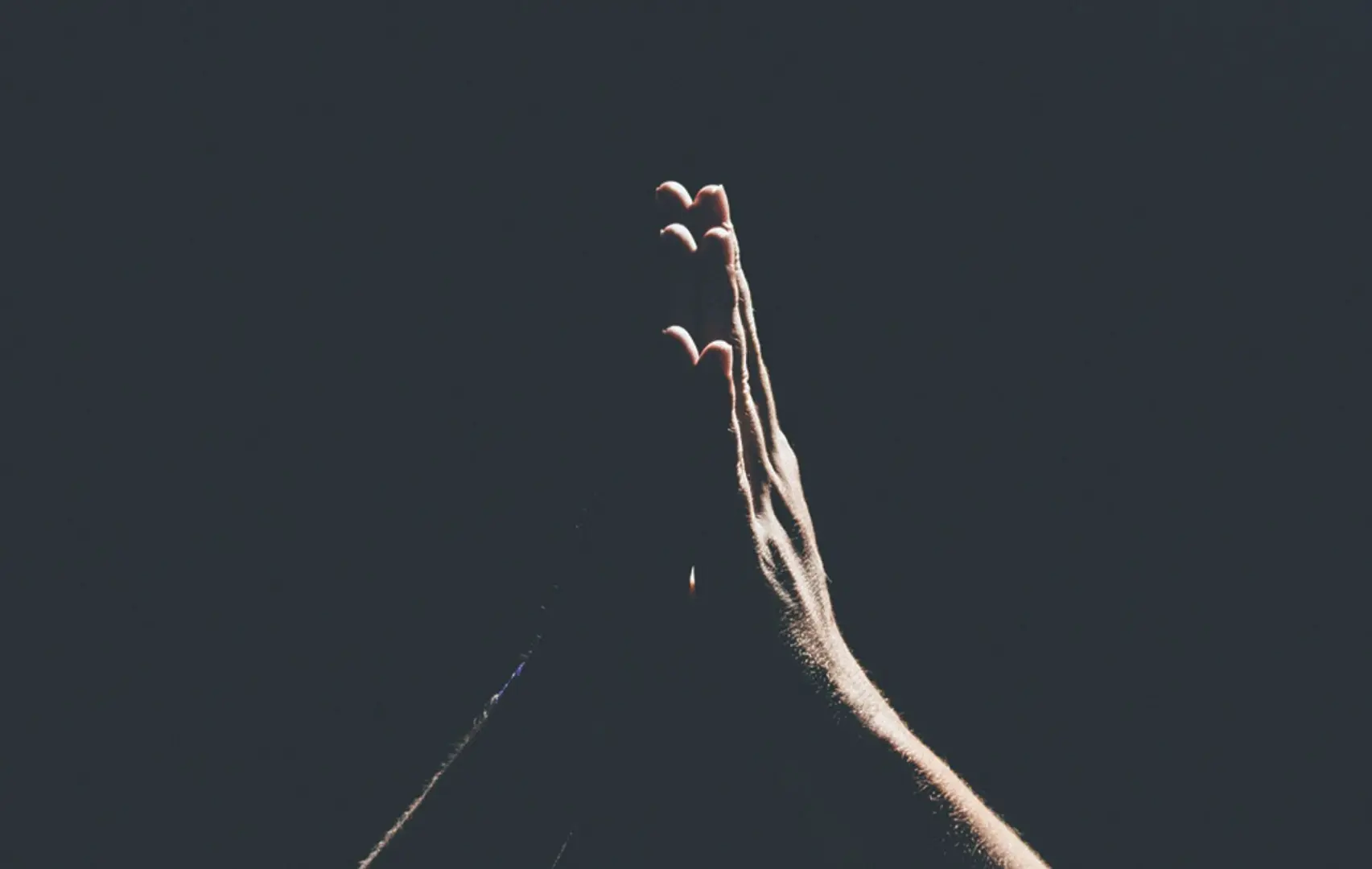 Hands praying in the dark.