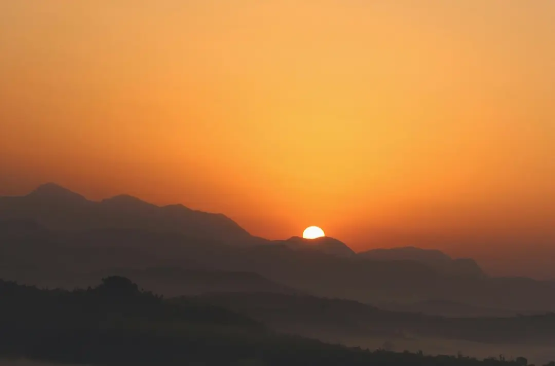 A photo of the sun rising over icy mountains.