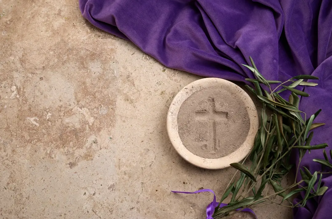 An image of a purple cloth with a olive branches and cross laid over it