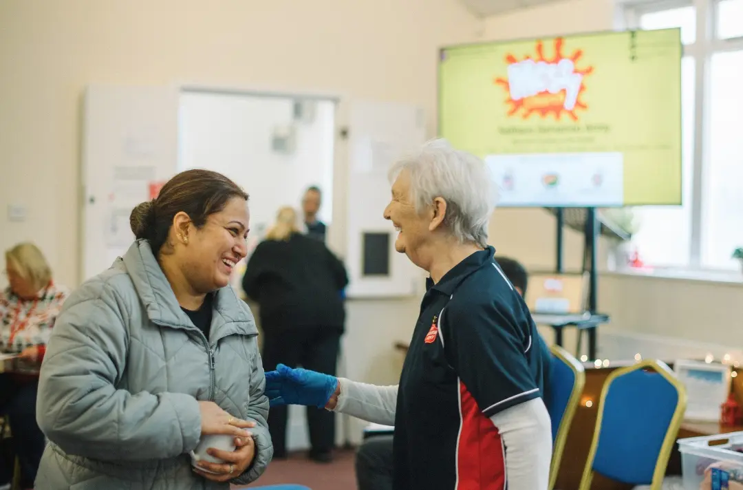 A photo shows two people from different generations talking at a Messy Church event.