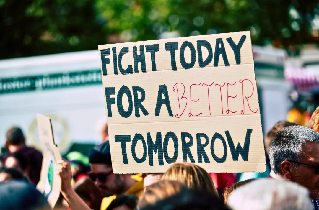 A photo shows someone holding a handmade sign that reads: Fight today for a better tomorrow.