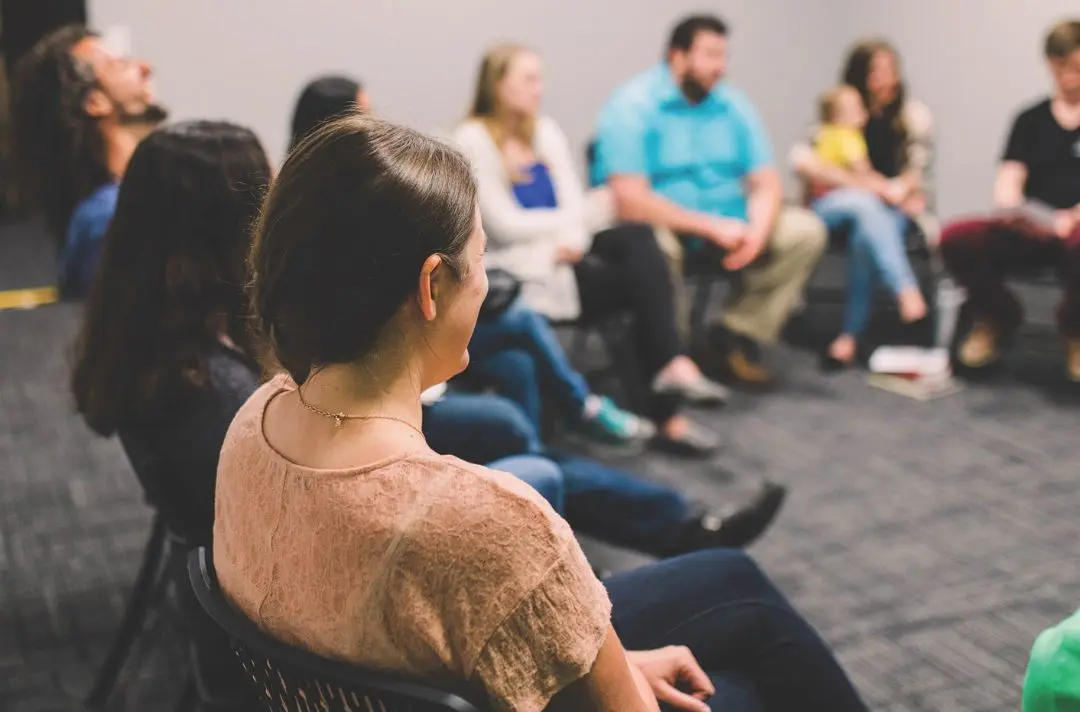 People sitting in a circle during a prayer meeting.