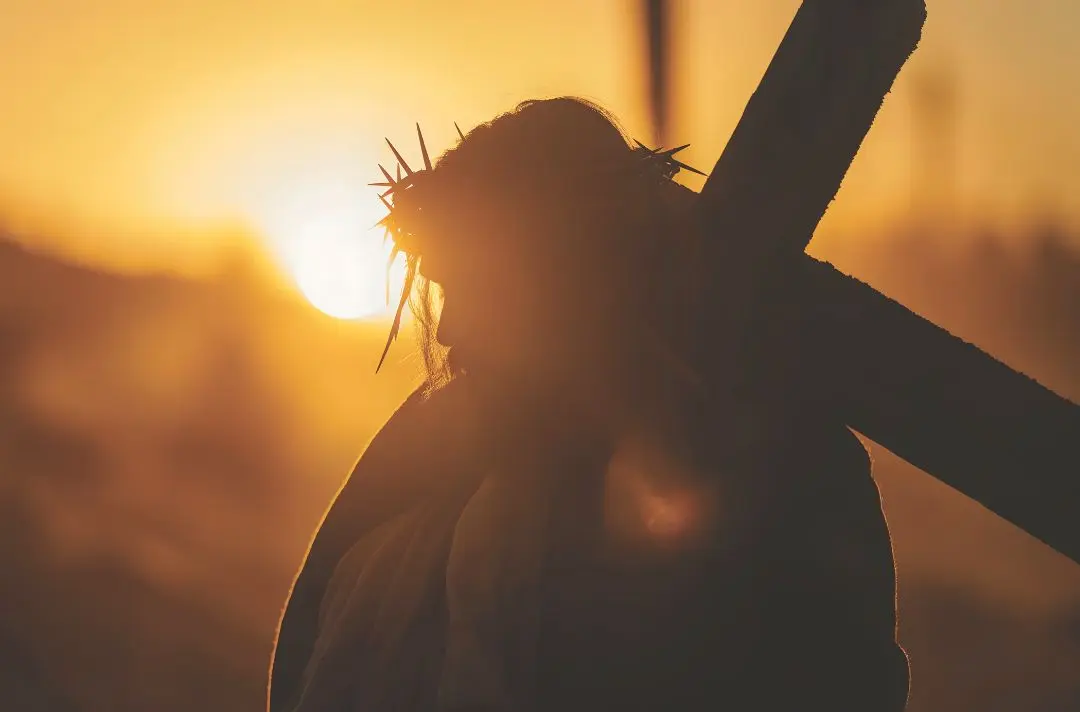 A silhouette of Jesus walking with the cross over his shoulder.