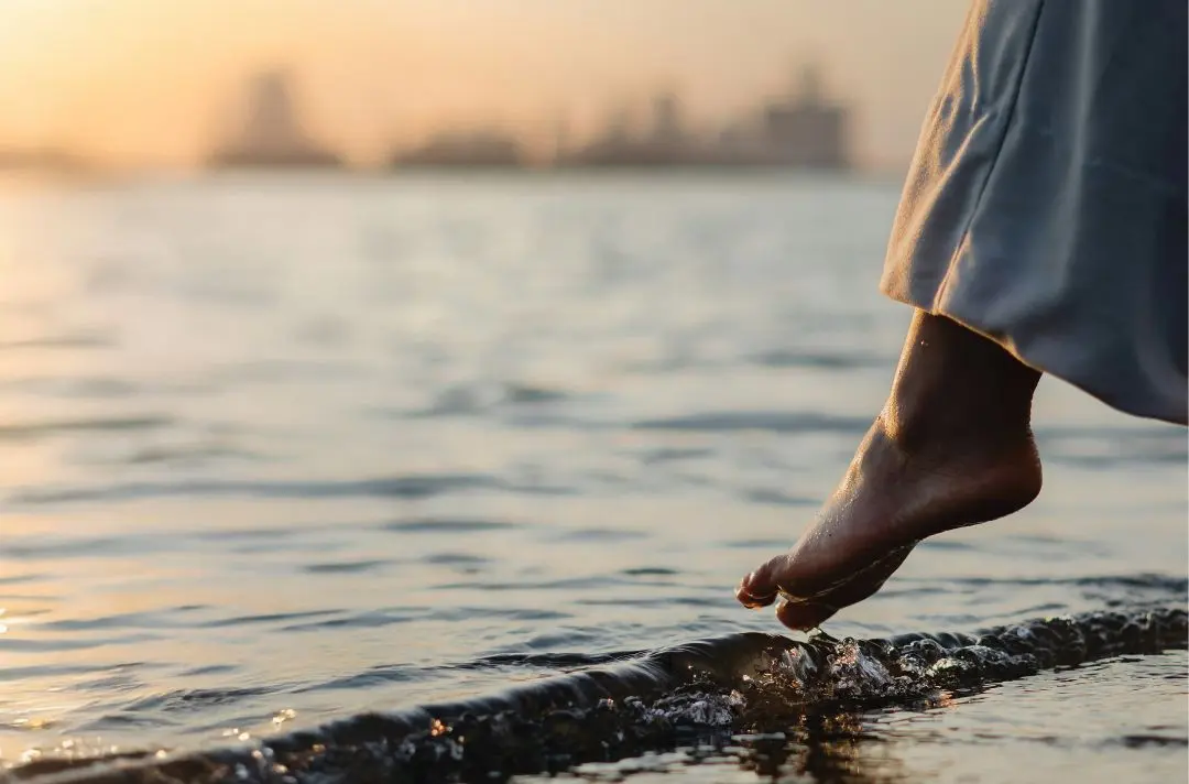 A person dipping their foot into the sea.