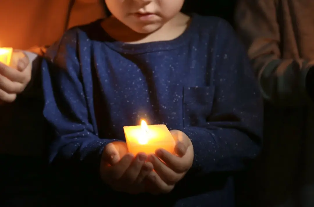 A small child holds a candle