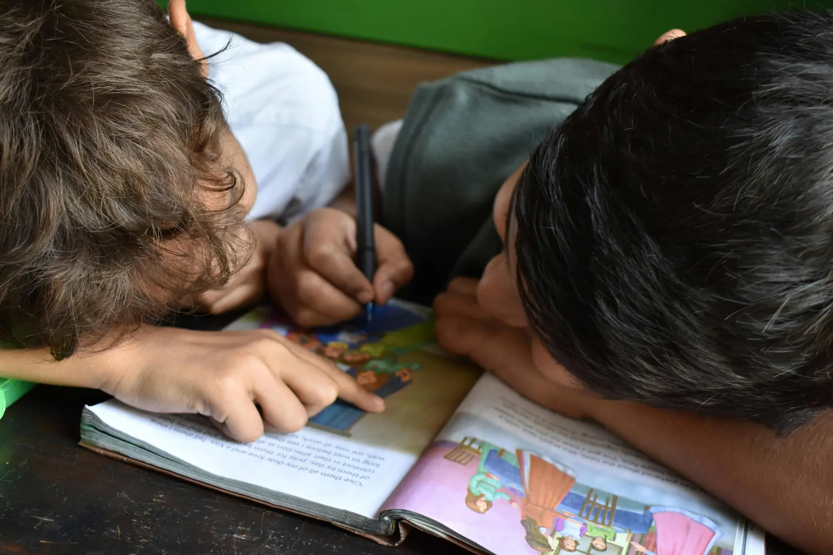 Photo image of 2 school aged children looking at a book together 