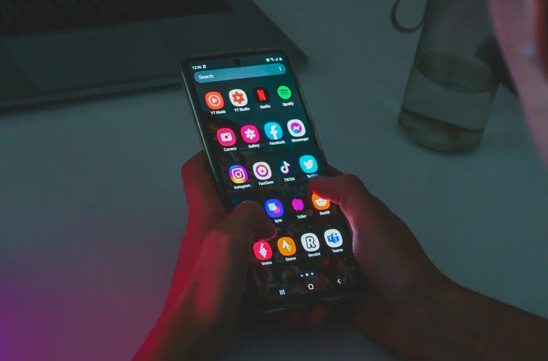 A photo shows someone using a smartphone at night.