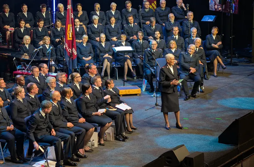 An image of Territorial Leader Jenine Main preaching a message to the newly ordained and commissioned officers on a platform. The Salvation Army flag can be seen in the background of the image. 