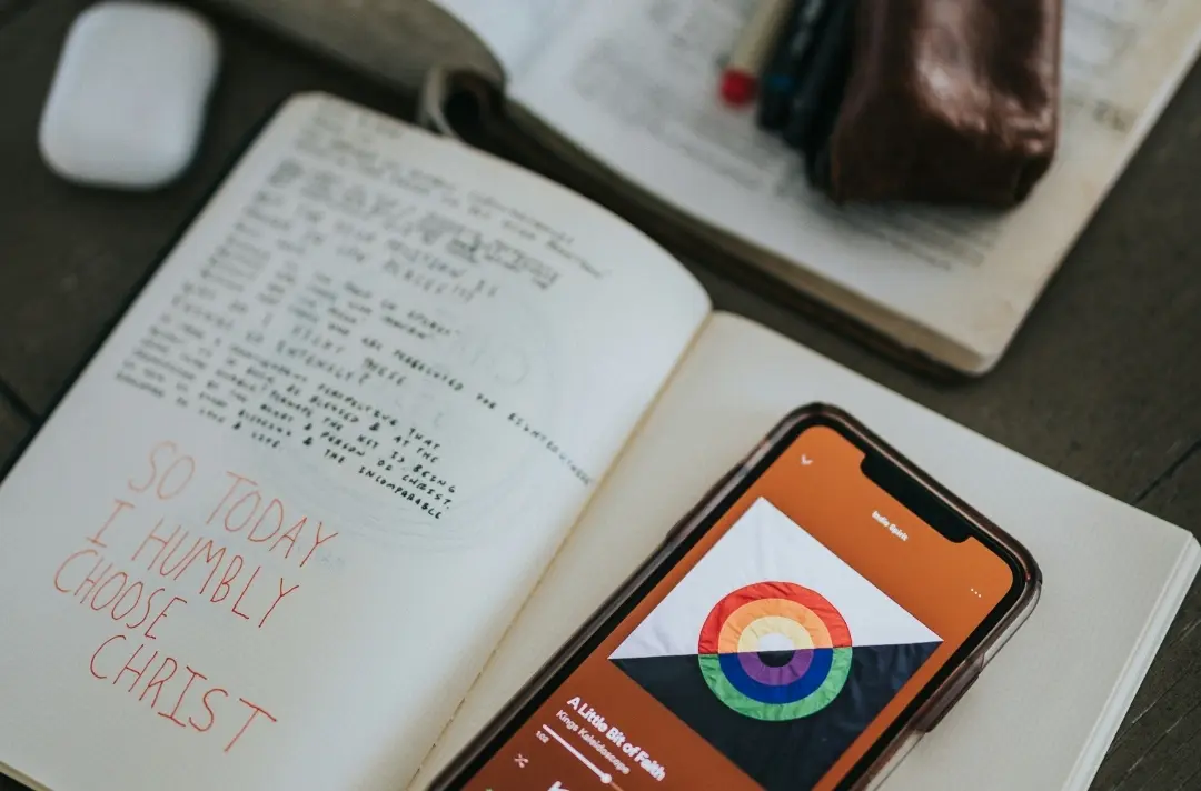 A picture of a phone open to Soptify next to an open Bible