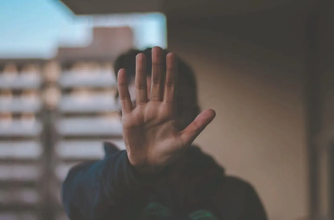 A person putting their hand up to cover their face as if to resist an insult or attack.