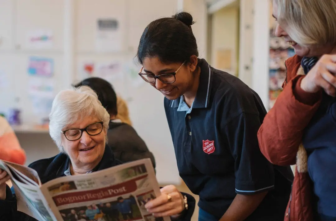 A photo shows people chatting together at an Open House event at Bognor Regis Corps. One of the people is wearing a Salvation Army branded shirt.