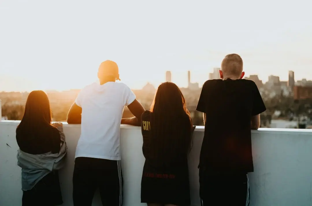 Four teenagers watch a sunset on top of a tower block.