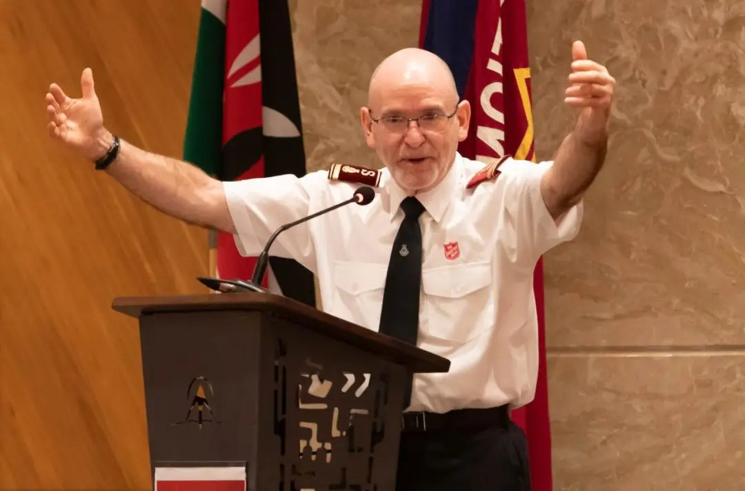General Lyndon Buckingham holds out his arms in a welcoming gesture.