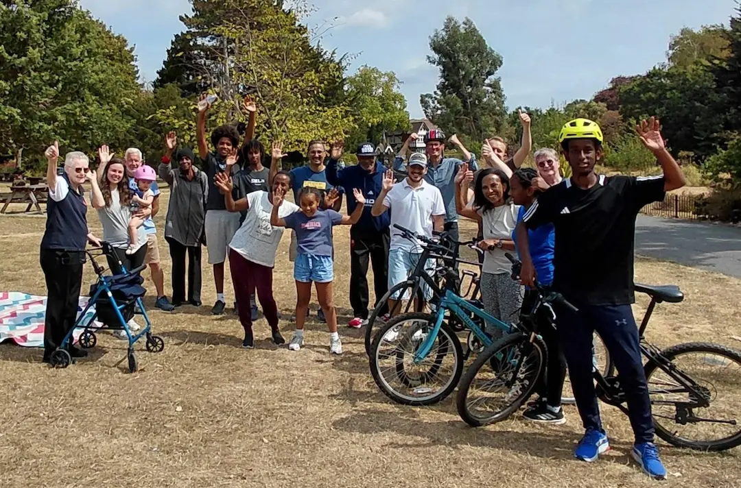Members of Harlesden Corps with their bikes and waving to the camera.