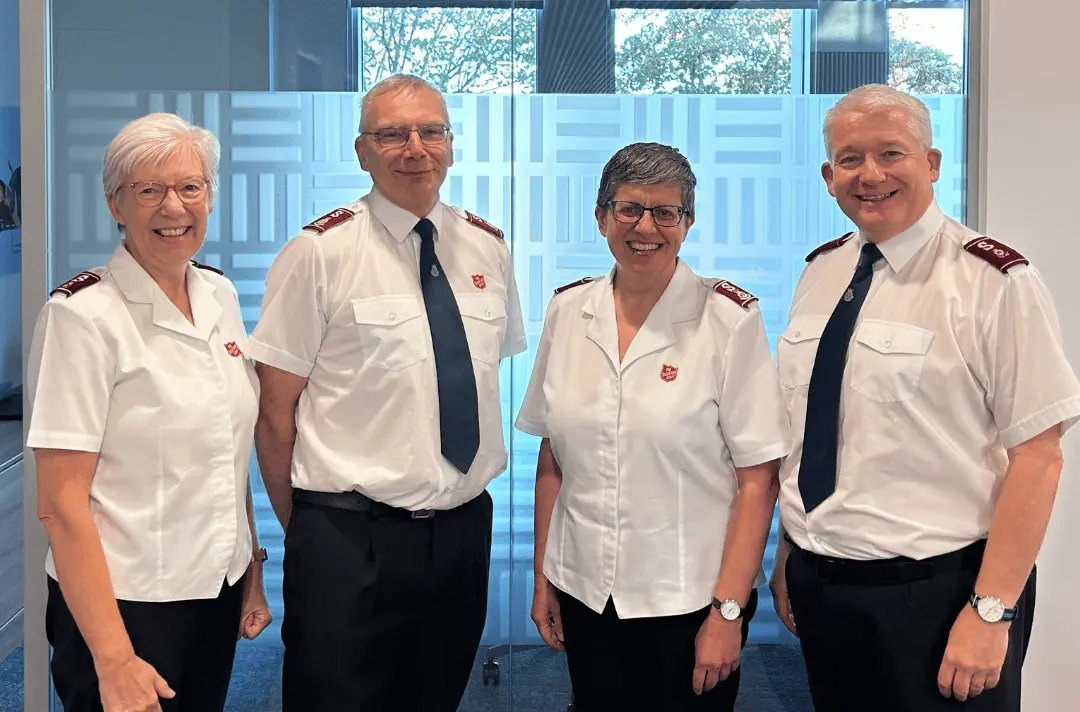 Four Salvation Army officers in uniform standing together in an office.