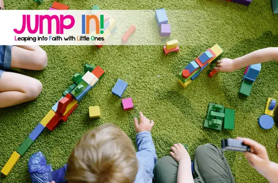 An overhead photo of toddlers playing with toys on a green mat